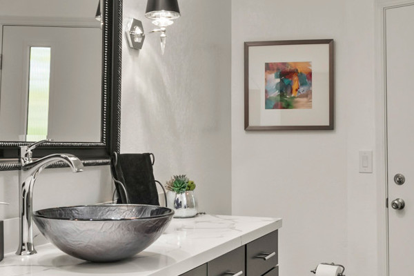 Modern hall bathroom in Loomis with sleek black cabinetry, a bowl sink, and marble countertop
