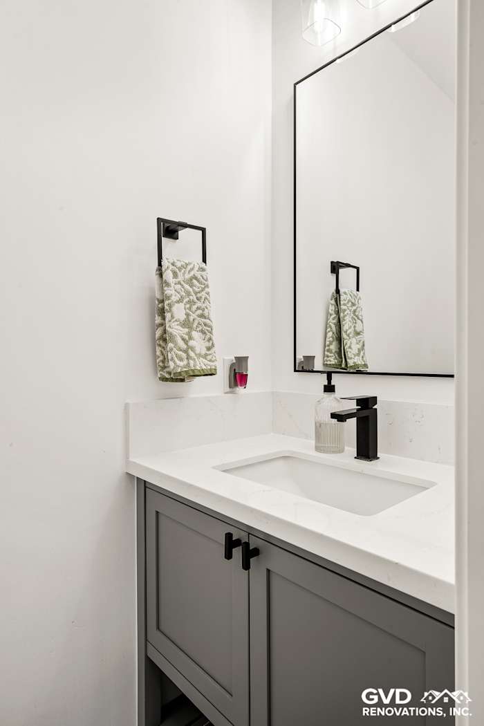 Modern bathroom remodel with sleek gray cabinetry, white countertop, and elegant wall-mounted mirror in Antelope, CA