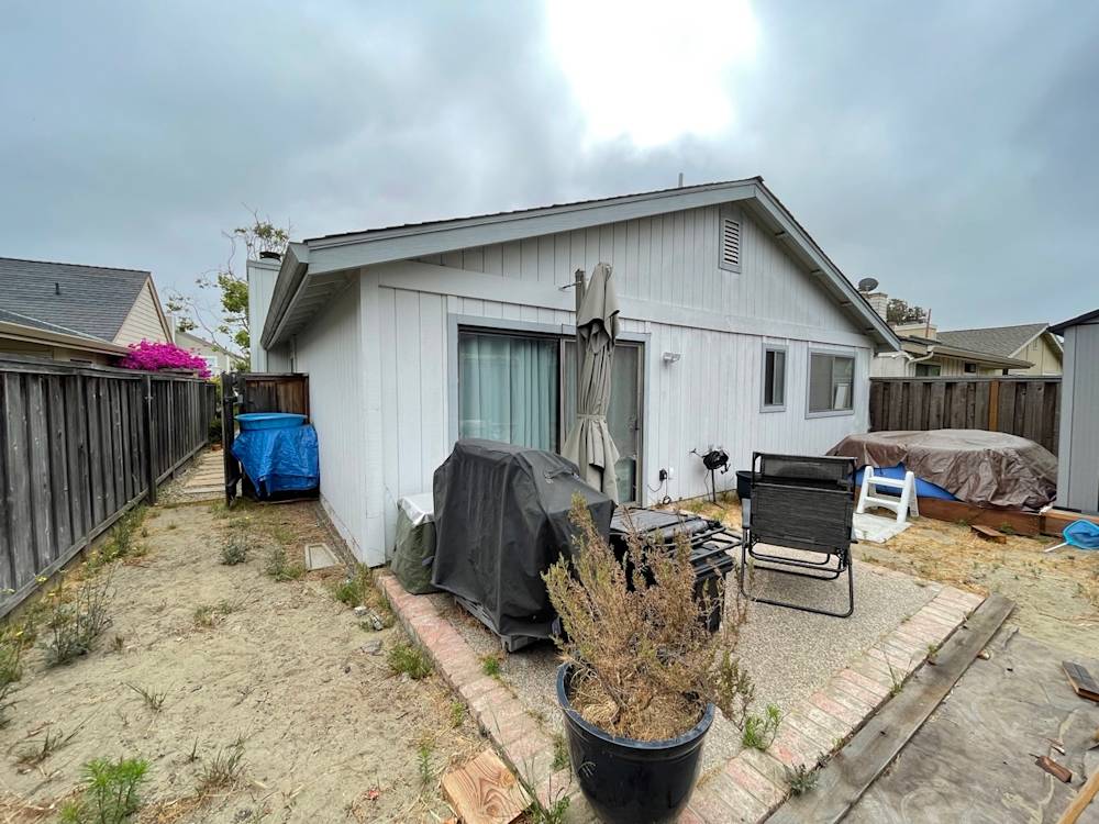 Overgrown backyard with concrete patio, furniture, and storage, located in Sacramento