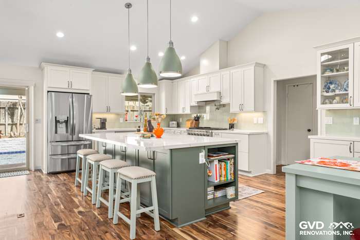 Modern kitchen remodel featuring custom island cabinets, green accent, quartz countertops, and stylish pendant lights