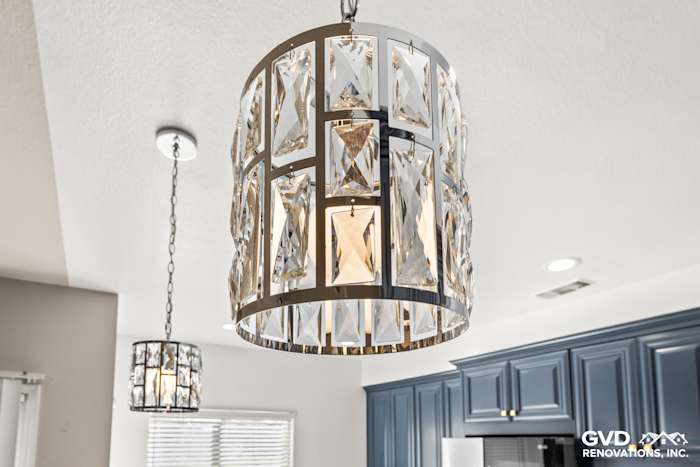Modern kitchen featuring elegant crystal pendant lights above a stylish blue cabinet setup