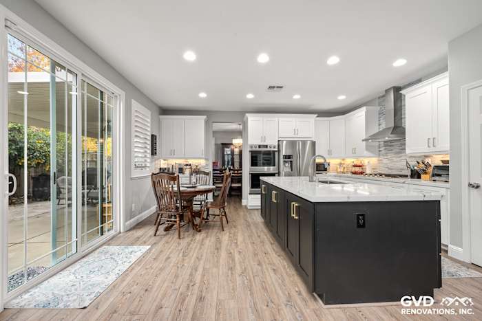 Modern kitchen with Cambria countertops, custom cabinets, and dining area, featuring light wood flooring and sliding glass