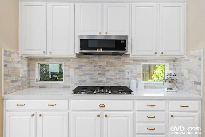 Modern kitchen featuring white cabinetry, quartz countertops, and a mosaic tile backsplash in Sacramento