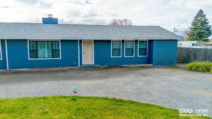 Sonoma home exterior showcasing James Hardie siding in Evening Blue with Arctic White trim, gravel driveway, and green lawn