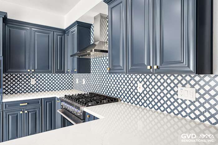Elegant blue cabinetry and white quartz countertops with a geometric backsplash in a Sacramento kitchen remodel