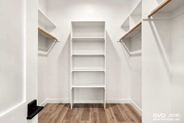 Spacious walk-in closet with white shelving and wooden rods in new construction home, Paradise, CA