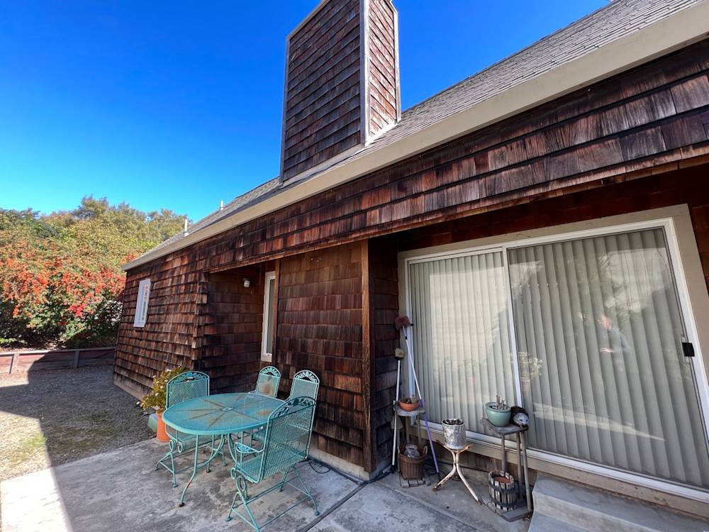 Weathered wooden siding and concrete patio with green outdoor furniture in Sacramento backyard
