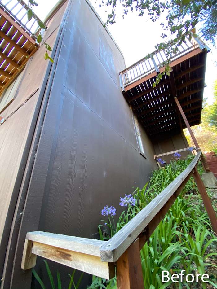 Before image showing a home's side with dark, uninstalled James Hardie siding and wooden deck above