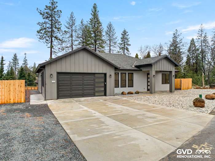 New construction home exterior features James Hardie siding in Sea Grass, Milgard black windows, and a spacious driveway