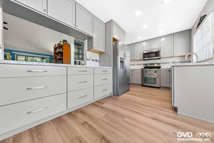 Modern kitchen remodel featuring gray cabinetry, quartz countertops, stainless steel appliances, and hardwood flooring
