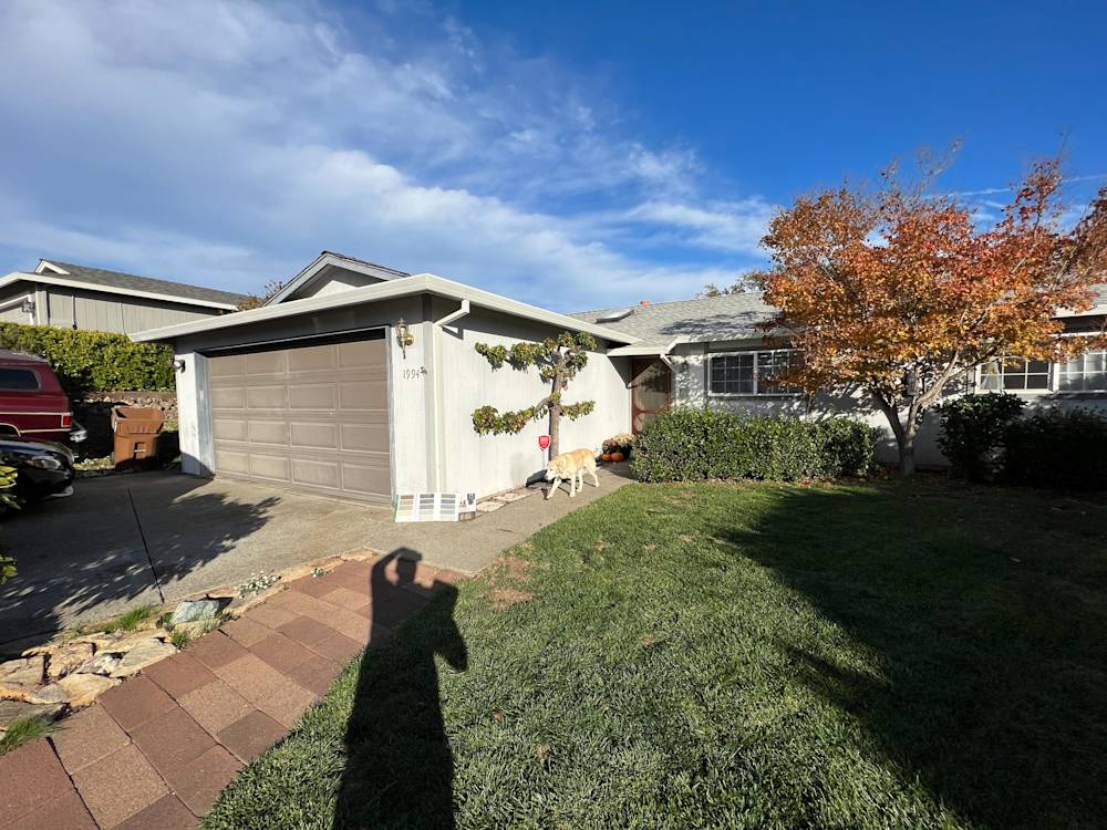 Single-story home exterior with gray siding, manicured lawn, and vibrant autumn foliage in Sacramento