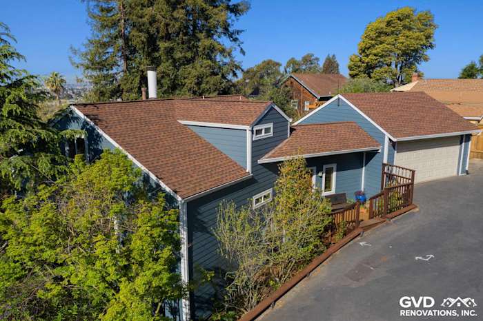 Modern home exterior featuring James Hardie lap siding in blue, brown roof, and landscaped yard in Oakland
