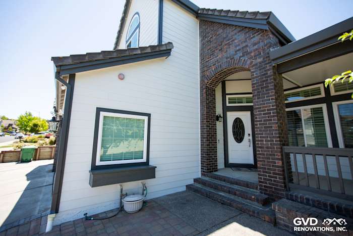 Arctic White James Hardie Lap Siding on home exterior with Iron Gray HardieTrim and brick accents in Hayward, CA
