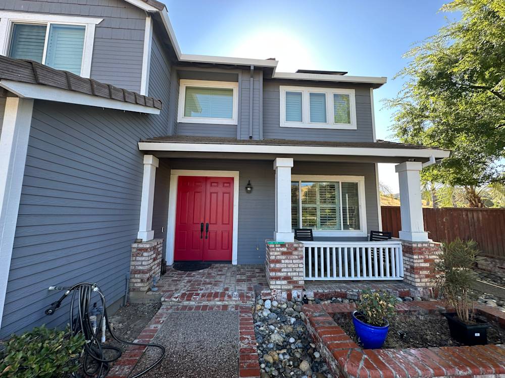 Charming Sacramento home with grey siding, red door, brick accents, and landscaped front yard