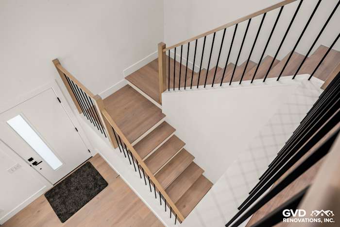 Modern staircase with wooden steps, black railing, and light hardwood flooring in Antelope home remodel