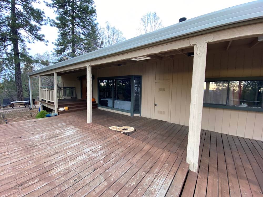 Spacious wooden deck surrounded by trees, featuring beige walls and large glass doors in Northern California