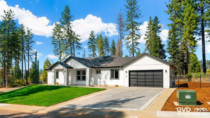 Modern single-story home exterior in Paradise, CA, featuring a mix of white siding and dark trim, expansive lawn, and paved