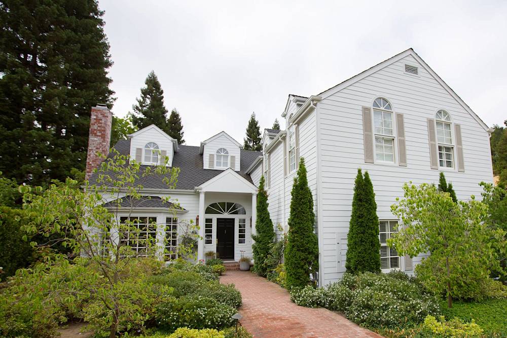 Fresh white siding enhances this modernized home's curb appeal with vibrant landscaping