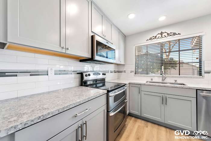 Modern kitchen with gray cabinets, quartz countertops, stainless steel appliances, and subway tile backsplash in Carmichael