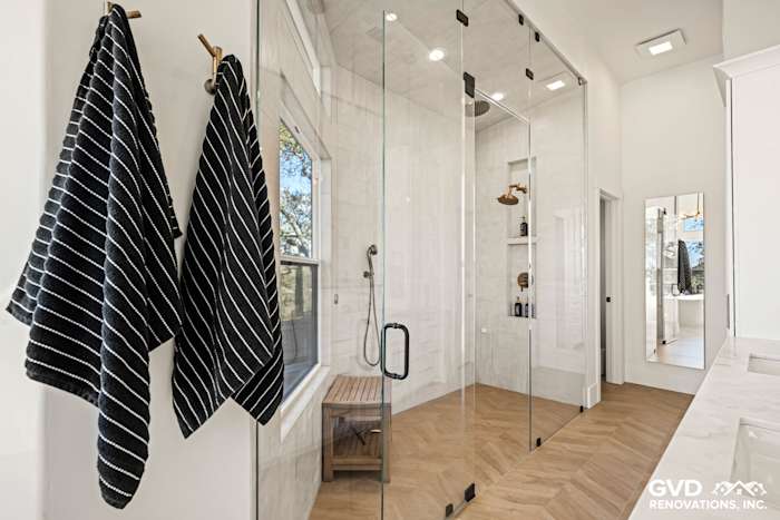 Elegant bathroom featuring a zero-threshold steam shower, glass enclosure, and herringbone tile flooring