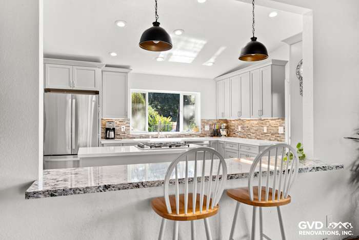 Bright modern kitchen with granite countertops, white cabinets, and a view of the outdoor greenery