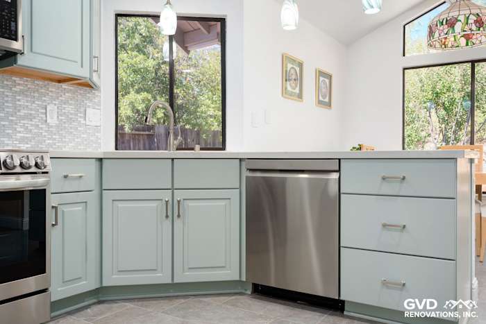 Light blue kitchen cabinets with stainless steel dishwasher, quartz countertop, and mosaic tile backsplash in Cameron Park