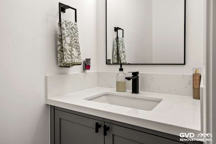 Modern bathroom with gray cabinetry, quartz countertop, black fixtures, and a sleek mirror in Antelope home