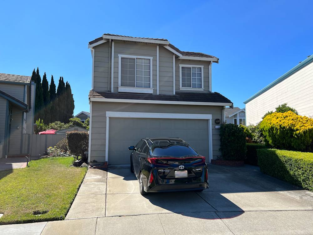 Charming Sacramento home exterior with gray siding, trimmed shrubs, and a black sedan in driveway