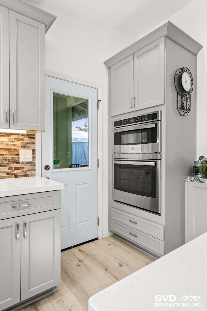 Modern kitchen remodel featuring gray cabinets, double ovens, and a stylish backsplash in Greenwood, CA
