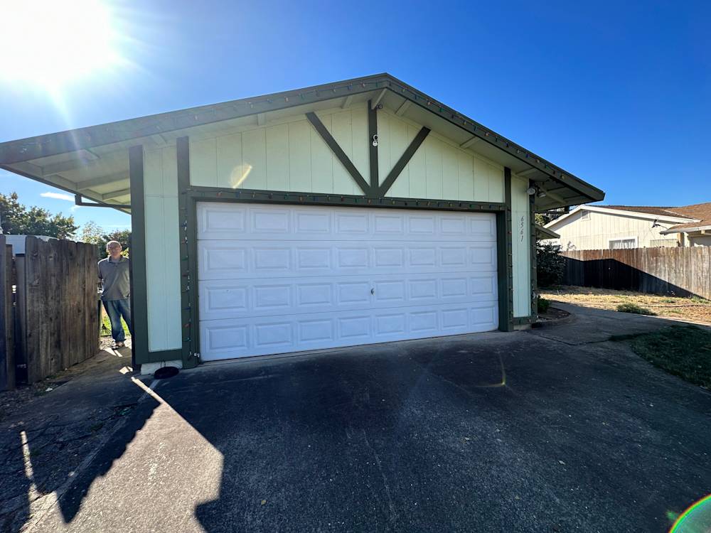 Single-story Sacramento home with a light green exterior and white garage door on concrete driveway