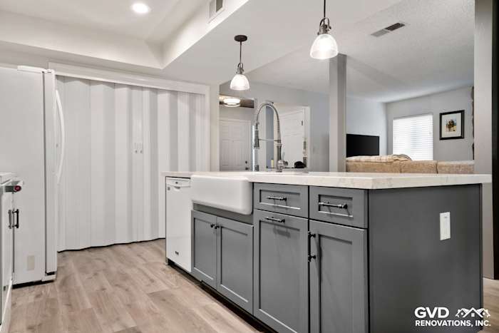 Modern kitchen remodel in Sacramento with gray cabinetry, quartz countertop, farmhouse sink, and pendant lighting