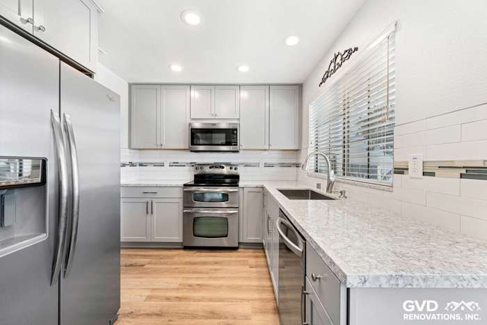 Modern kitchen remodel featuring gray cabinetry, quartz countertops, stainless steel appliances, and subway tile backsplash