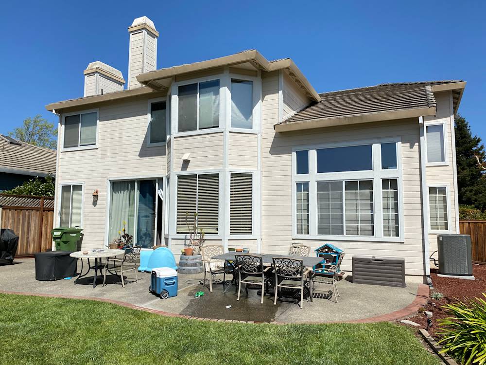Light-colored two-story home in Sacramento with large windows and patio furniture in backyard