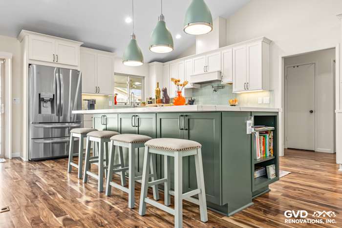 Modern kitchen with green island cabinets, white quartz countertop, pendant lights, and wood flooring in Carmichael, CA
