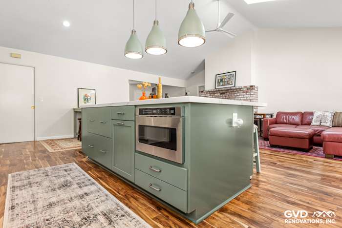 Modern kitchen remodel featuring custom green island cabinets, stainless steel appliances, and pendant lighting