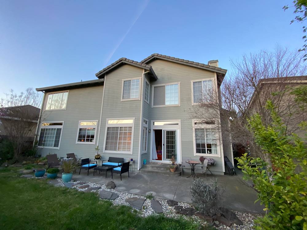 Two-story light gray home with a concrete patio and landscaped garden in Sacramento