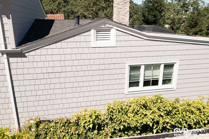 James Hardie Shingle Siding in Pearl Gray on home exterior, featuring a white window and stone chimney