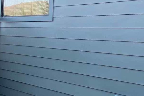 Dark blue James Hardie siding on home exterior with wooden deck and lush greenery in Mill Valley