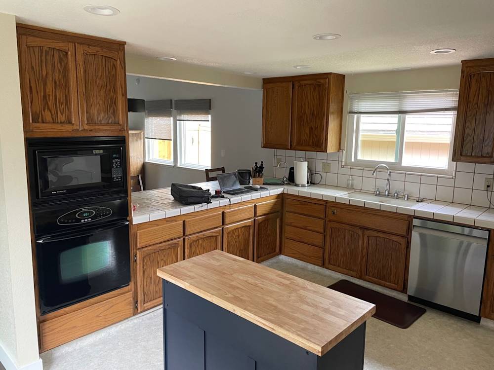 Outdated kitchen with wooden cabinets, tiled counters, and simple appliances in Fair Oaks, Northern California