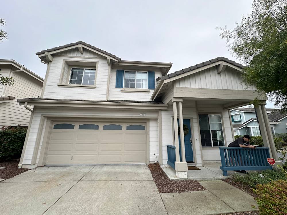 Two-story home exterior in Sacramento with light siding, blue accents, and a two-car garage