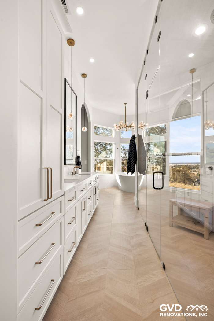 Bright and airy master bathroom featuring sleek white cabinetry, herringbone tile floors, and a glass steam shower