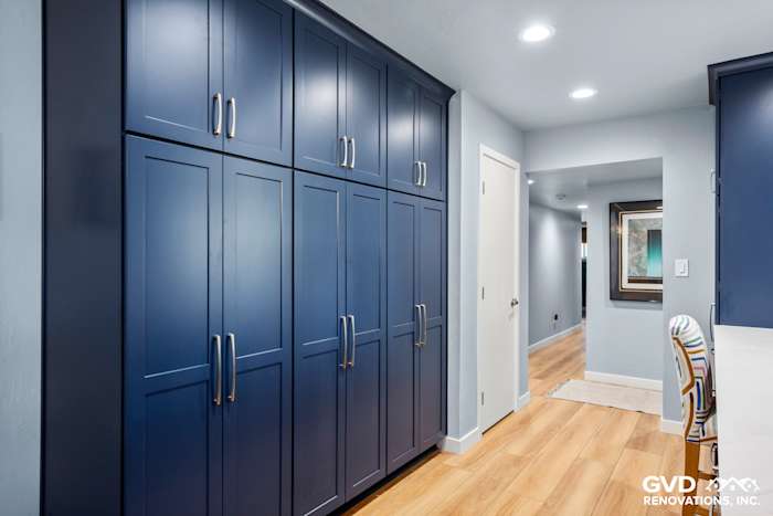 Navy blue cabinets with sleek handles in a modern kitchen remodel, featuring light wood flooring and bright lighting