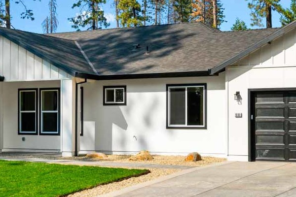 New construction home in Paradise, CA, featuring a modern design, white siding, and black garage doors