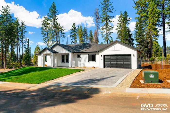 New construction home in Paradise, CA, featuring a modern design, white siding, and black garage doors