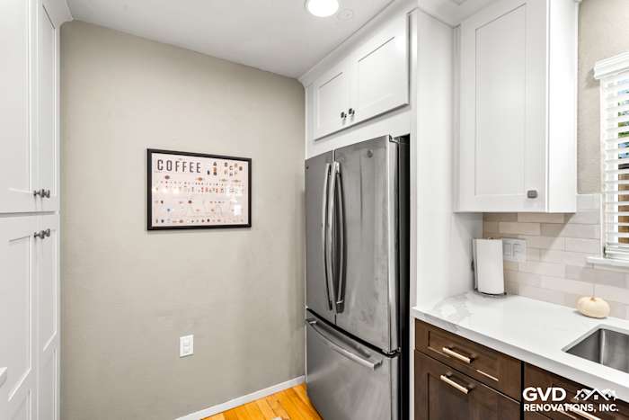 Modern kitchen with stainless steel refrigerator, white cabinetry, and light gray walls in Davis, CA