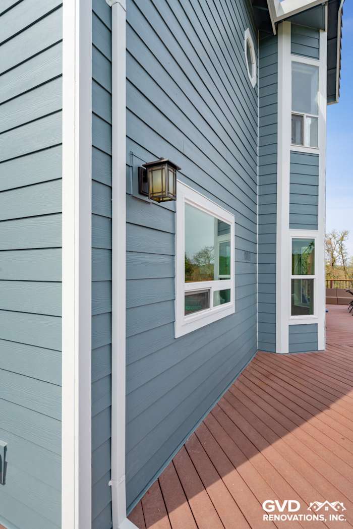 Newly installed blue James Hardie siding on a home's exterior with modern lantern and large window