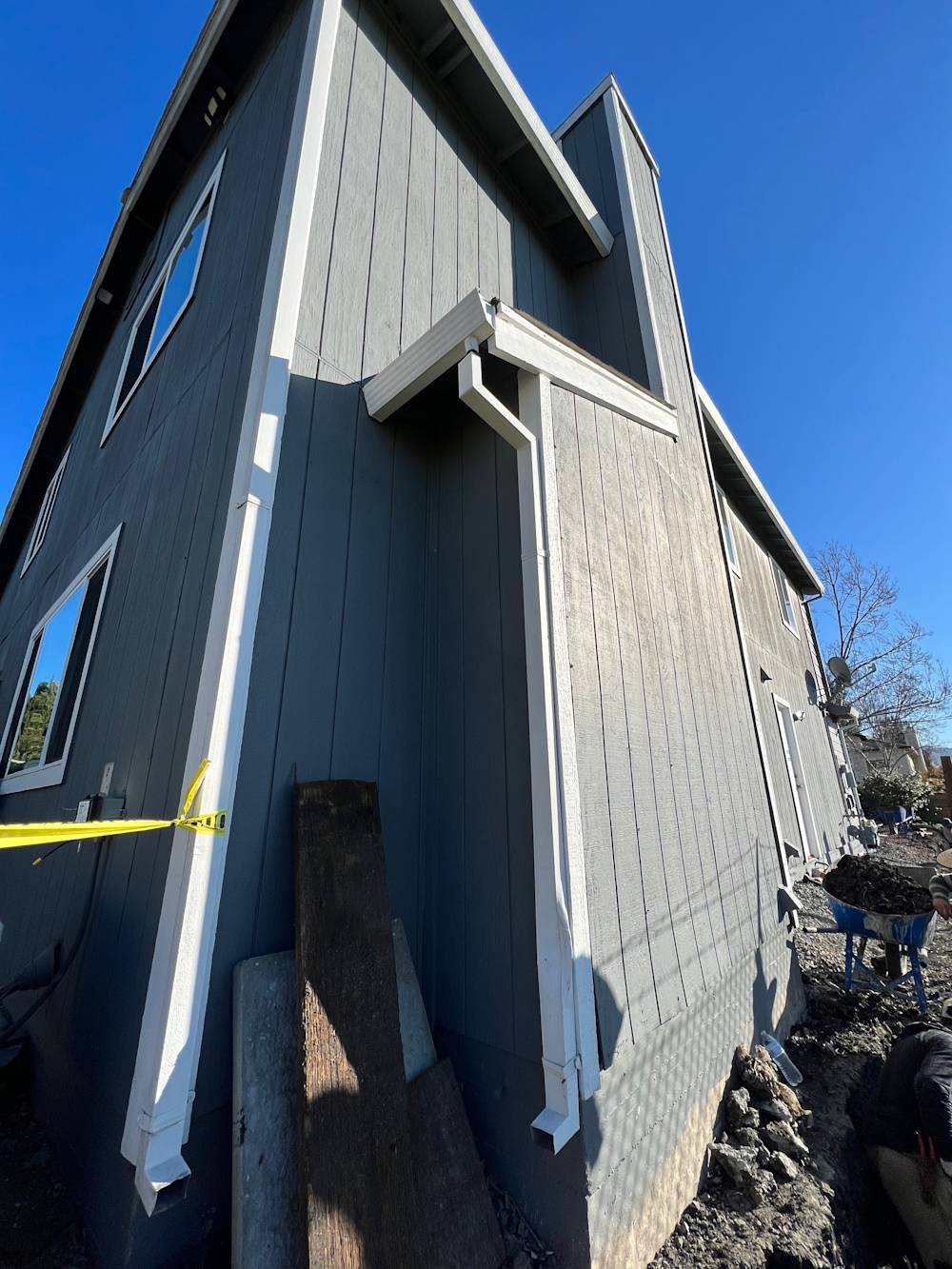 Gray exterior siding with existing concrete foundation, small yard visible in Sacramento sunlight