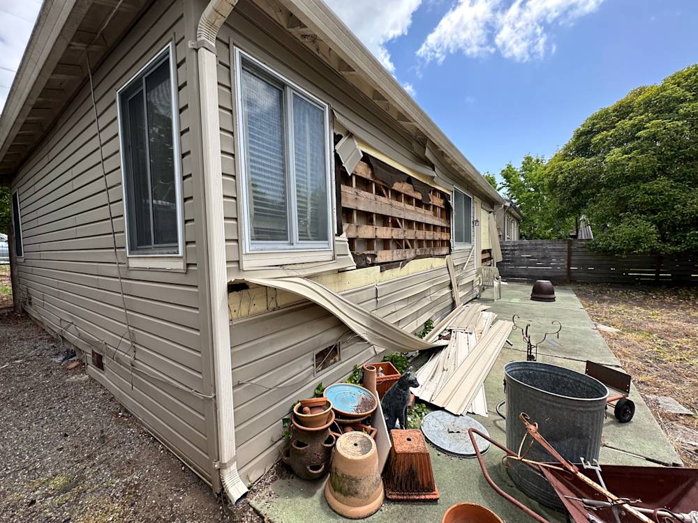 Damaged siding and cluttered yard at a Sacramento remodeling project site