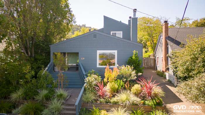 Corte Madera home featuring James Hardie Evening Blue siding and Arctic White trim, surrounded by lush landscaping