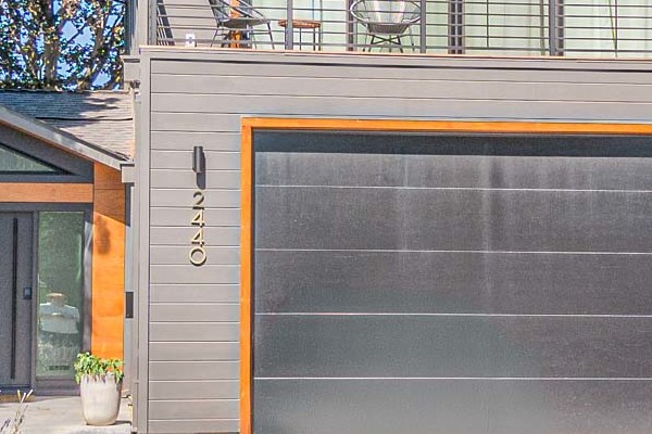 Modern home exterior featuring James Hardie V Groove Artisan Siding in gray, with orange accents and landscaped walkway